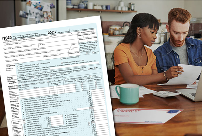 An IRS form 1040 in the foreground while two people fill out tax forms on a table in the background.