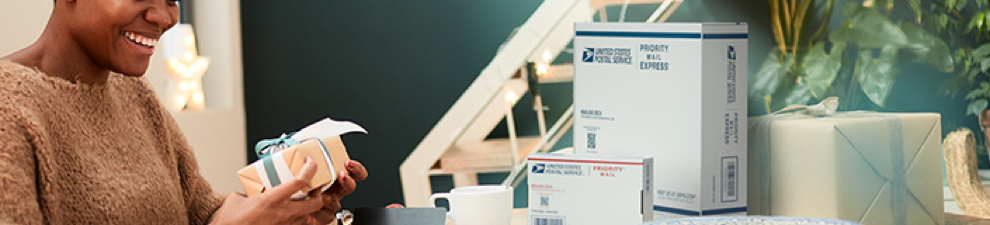 A woman prepares to pack and ship a holiday gift in a Priority Mail box.