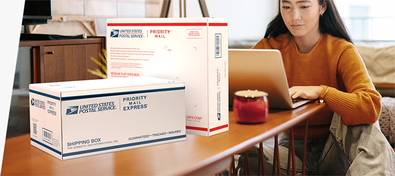 Woman on a laptop preparing to send a Priority Mail Express International® box and a Priority Mail International® box.