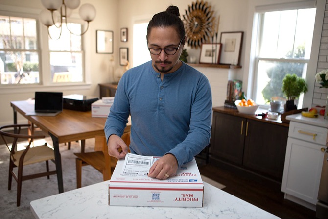 A person placing a Click-N-Ship label on a Priority Mail package.