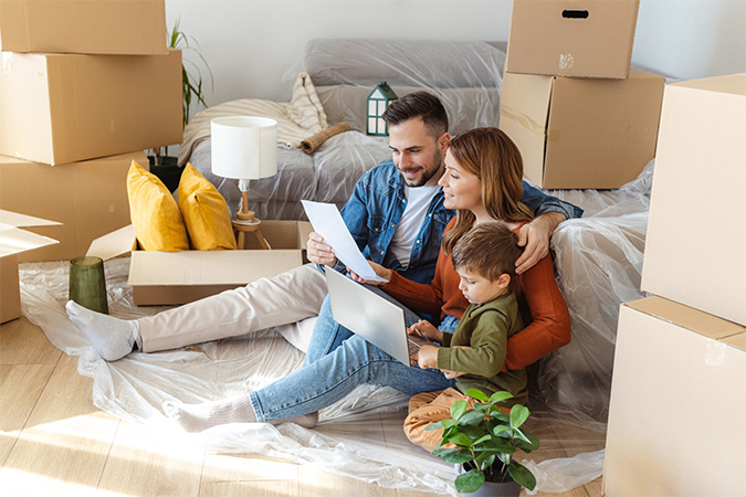 A family sitting together on a laptop surrounded by moving boxes.